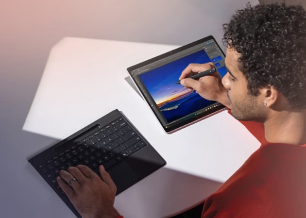 A man using his Surface Keyboard with his left hand, while drawing on his Surface Pro with his right hand. 